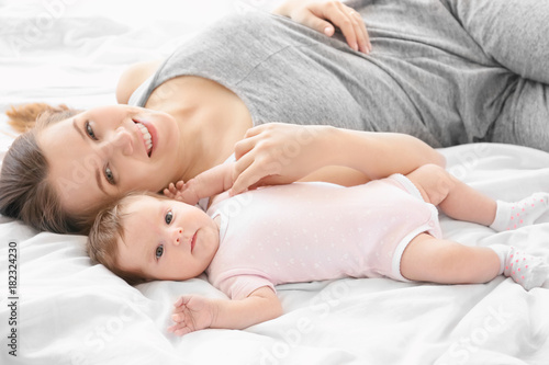 Young mother with baby on bed at home