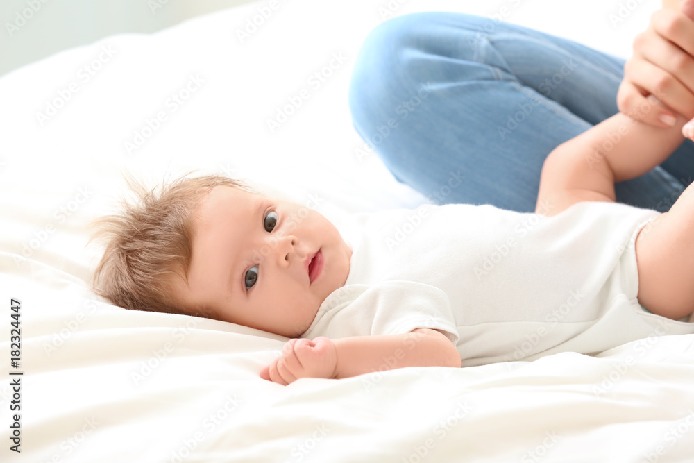 Young mother playing with cute baby on bed at home Young mother playing with cute baby on bed at home