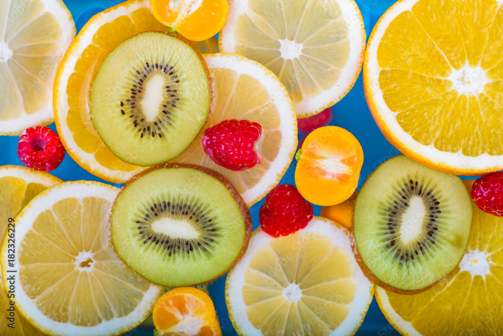 Fresh raspberry, kiwi, orange, lemon and orange slices floating in water on white Fresh raspberry, kiwi, orange, lemon and orange slices floating in water on white