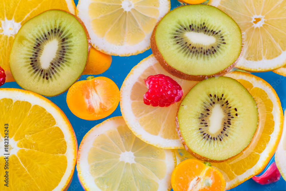Fresh raspberry, kiwi, orange, lemon and orange slices floating in water on white Fresh raspberry, kiwi, orange, lemon and orange slices floating in water on white