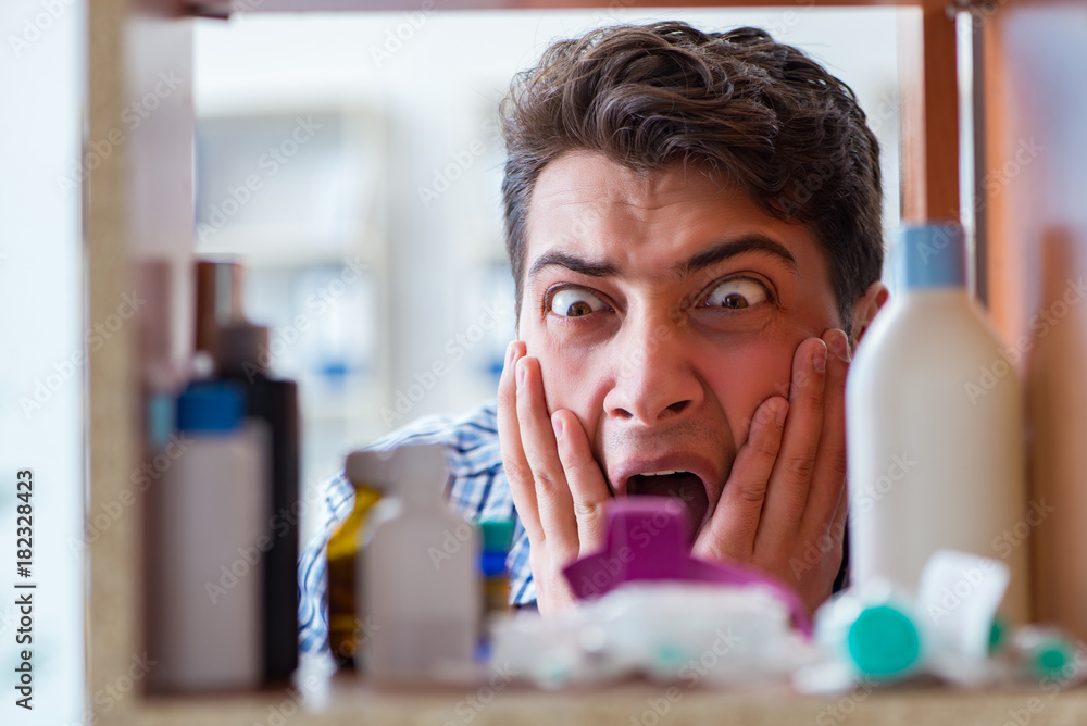Sick ill man looking for medicines at farmacy shelf Sick ill man looking for medicines at farmacy shelf