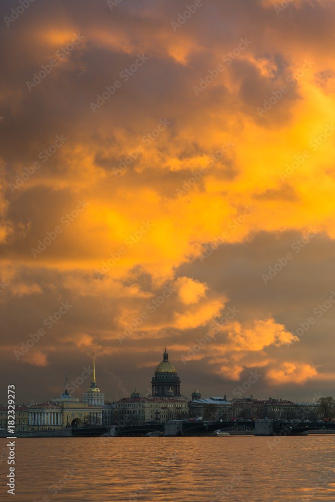 beautiful dramatic orange sunset over St. Petersburg/St. Isaac's Cathedral on the background of a beautiful orange sunset sky/clouds illuminated by the setting sun/reflection of the sky in water