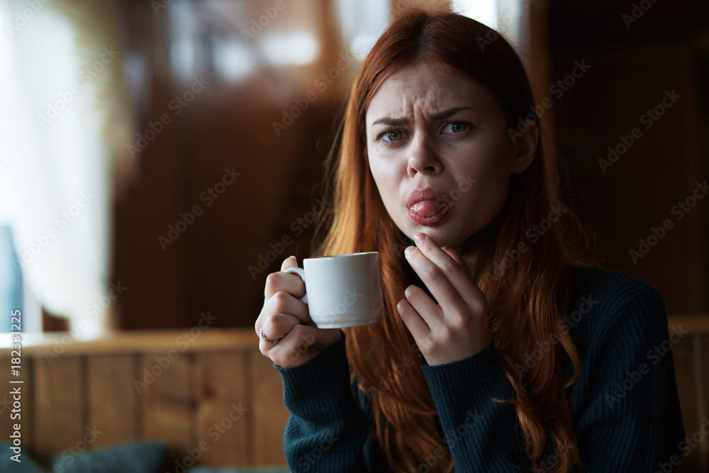 Young beautiful woman drinks coffee in a cafe in winter and shows tongue Young beautiful woman drinks coffee in a cafe in winter and shows tongue