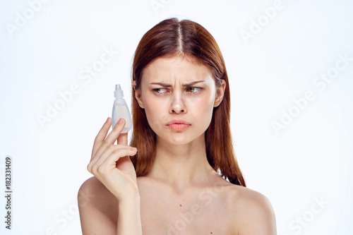 Young beautiful woman on white isolated background holds drops for eyes, medicine