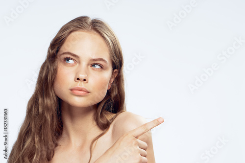 Young beautiful woman on white isolated background shows on empty space