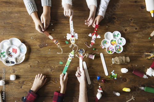 Little kids holding Christmas character decorated popsicle sticks photo