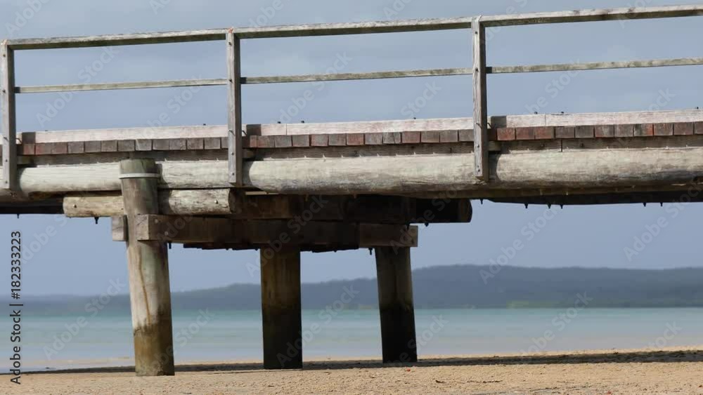Panning close-up shot of a wooden empty pier that runs from the beach and into the water. Panning close-up shot of a wooden empty pier that runs from the beach and into the water.