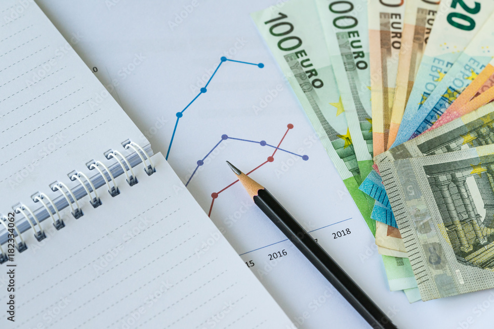 Pencil on printed chart, graph and paper note with pile of Euro banknotes as Euro economic review or debt analysis or check list conceptd Pencil on printed chart, graph and paper note with pile of Euro banknotes as Euro economic review or debt analysis or check list conceptd