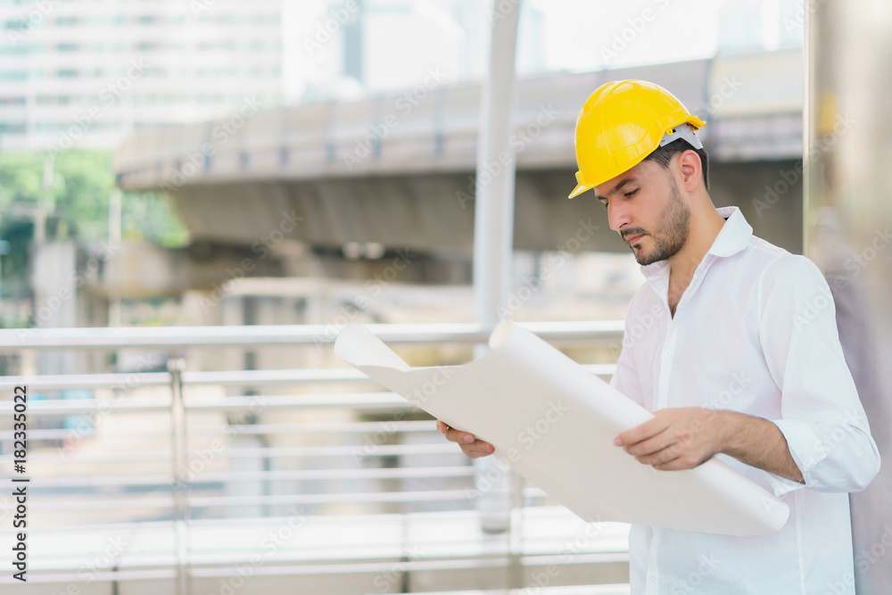 Engineer man wearing safety helmet and hold blueprint document at construction site. concept of work office, security consult, job control, development and business process. Engineer man wearing safety helmet and hold blueprint document at construction site. concept of work office, security consult, job control, development and business process.