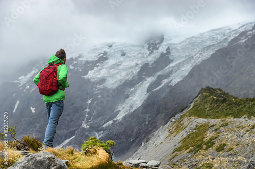 New Zealand hiker man hiking, enjoying view of snow capped mountain landscape in Hooker Valley track. Alps alpine background Active hiker standing . Mountaineering sport lifestyle.