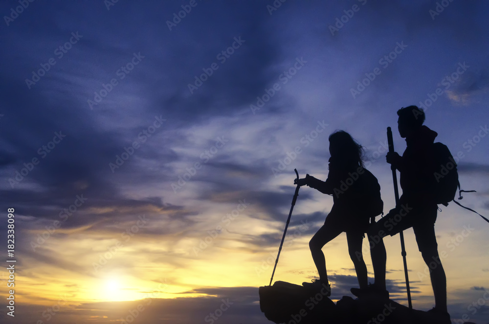Silhouette of a champion couple on the top of a rock mountain view of sunset.
