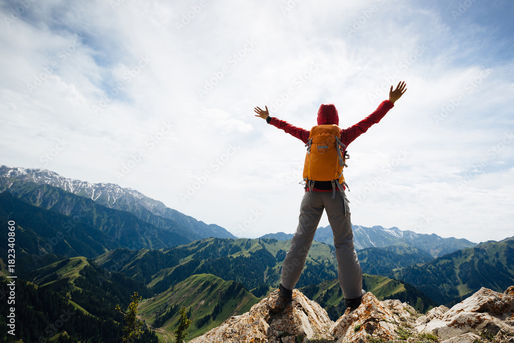 Successful woman backpacker enjoy the view on top of mountain rock Successful woman backpacker enjoy the view on top of mountain rock