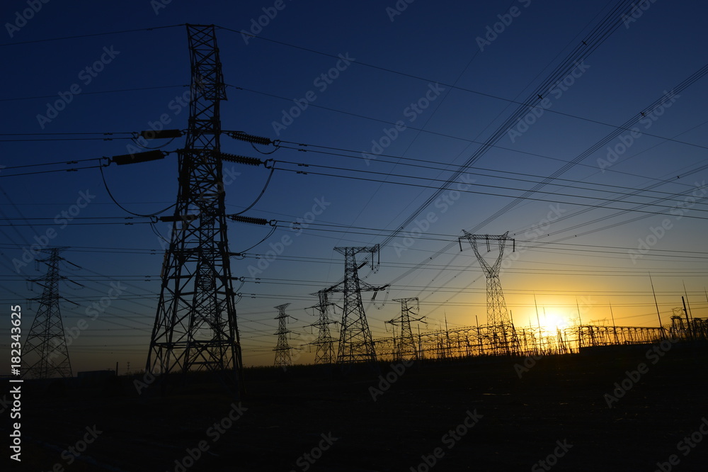 Fototapeta premium The silhouette of the evening electricity transmission pylon