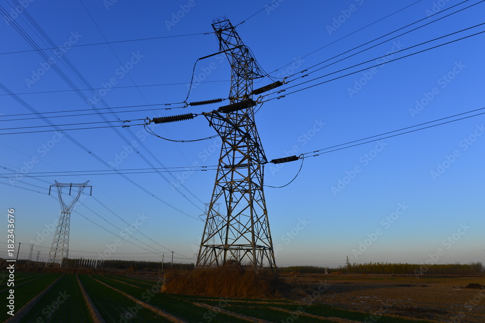 Fototapeta premium The silhouette of the evening electricity transmission pylon