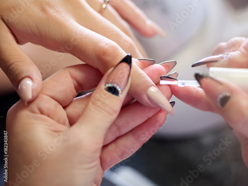 Woman in a nail salon receiving a manicure by a beautician with nail file woman