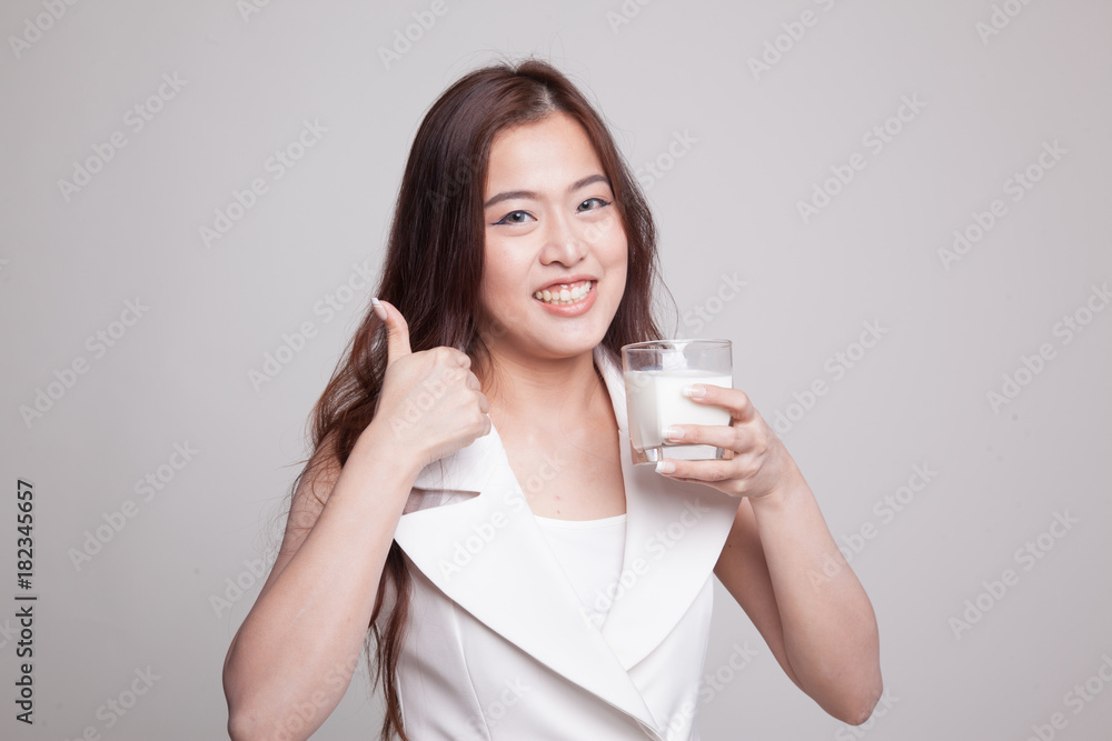 Healthy Asian woman drinking a glass of milk thumbs up. Healthy Asian woman drinking a glass of milk thumbs up.