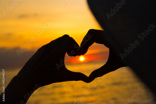 hands in heart shape at sunset on beach