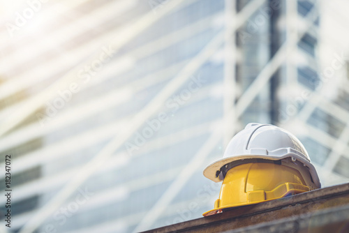white, yellow hard safety helmet hat for safety project of workman as engineer or worker, on concrete floor on city.
