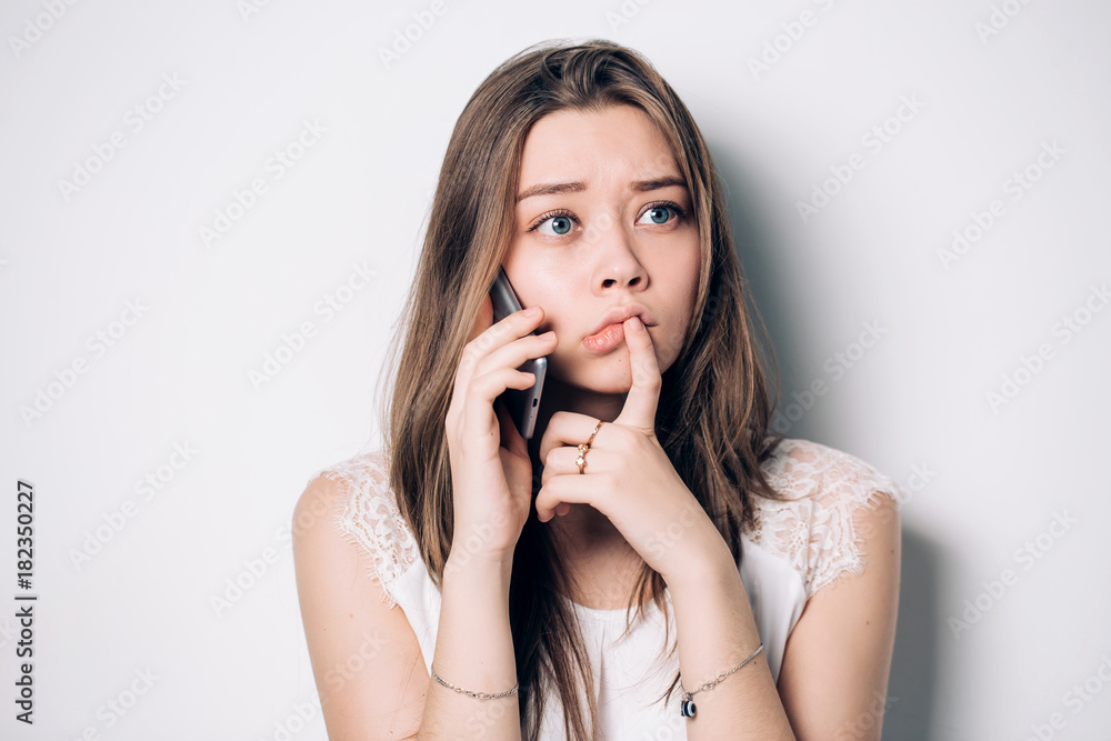 Frustrated annoyed sad woman with mobile phone. Young upset woman talking on phone in office. Unhappy, sad girl Frustrated annoyed sad woman with mobile phone. Young upset woman talking on phone in office. Unhappy, sad girl