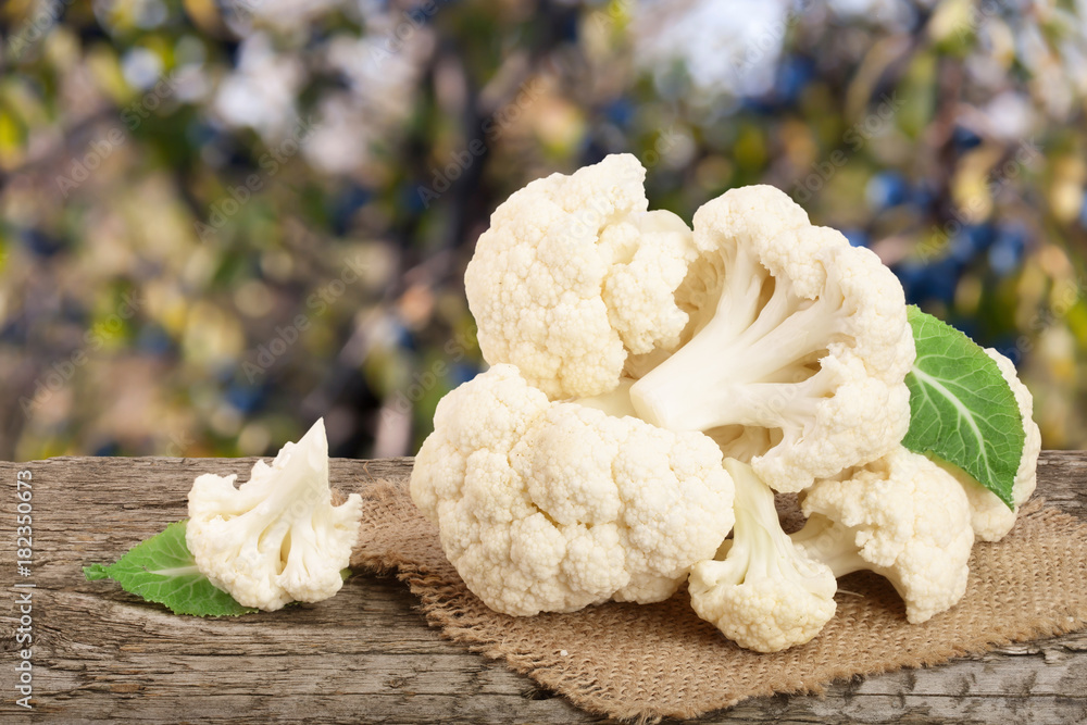 Piece of cauliflower on wooden table with blurred garden background Piece of cauliflower on wooden table with blurred garden background