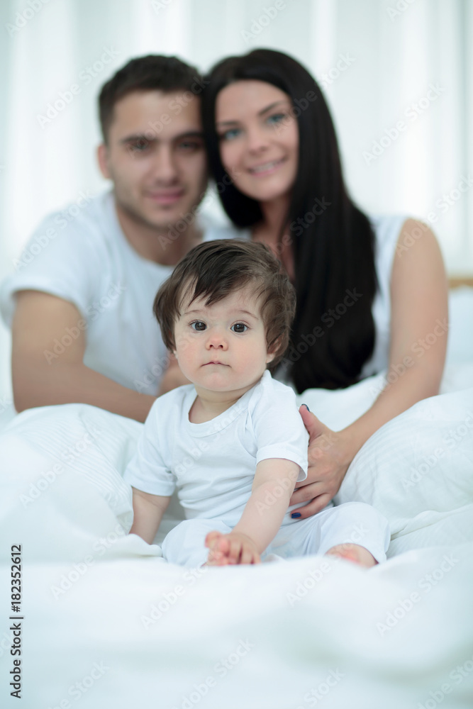 Happy couple and son sitting in bed