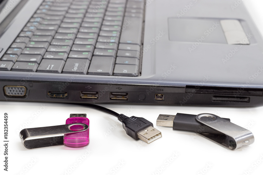 Two USB flash drives and USB cable against of laptop Two USB flash drives and USB cable against of laptop