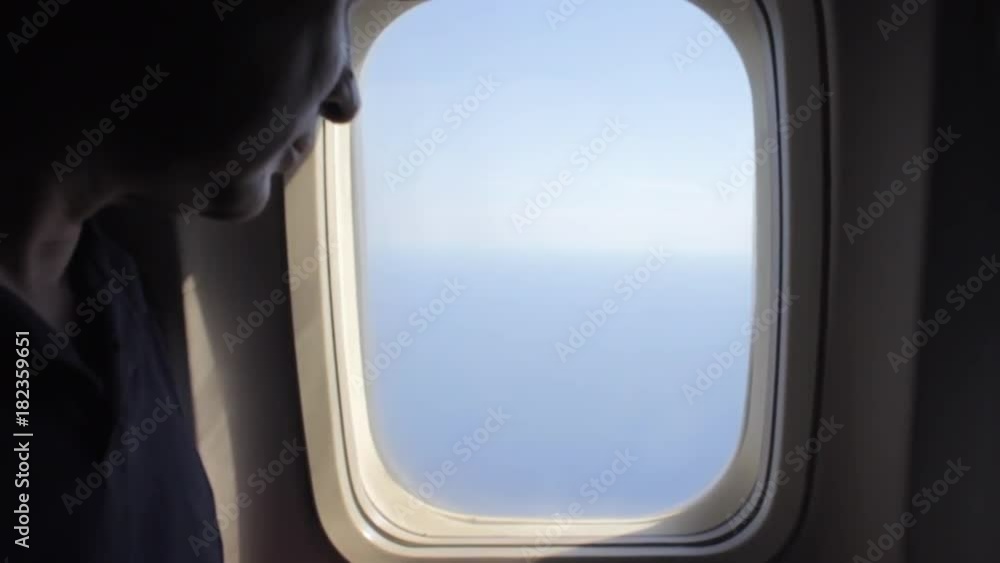 Man opens an airplane window and looks out during air travel. Happy. Man traveling by plane together. Tourism concept Man opens an airplane window and looks out during air travel. Happy. Man traveling by plane together. Tourism concept