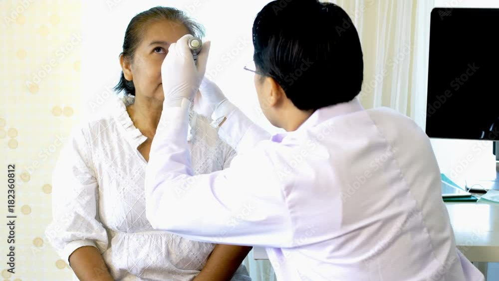 Asian young doctor examining female patient with flashlight