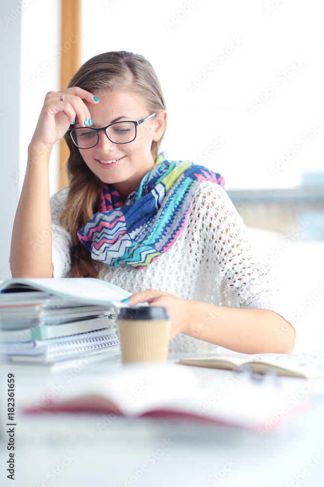 Young woman sitting at a desk among books. Student Young woman sitting at a desk among books. Student