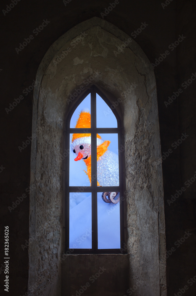 Fototapeta premium Snowman on the sled through a window in the castle