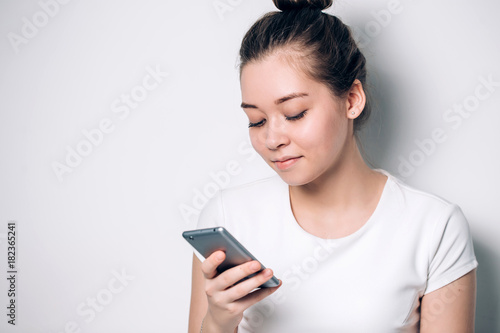 Woman typing text message on smart phone. Beautiful girl on white background, close-up