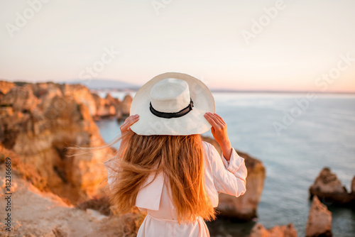 Woman enjoying great view on the rocky coastline during the sunrise in Lagos on the south of Portugal