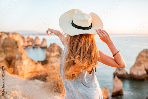 Woman enjoying great view on the rocky coastline during the sunrise in Lagos on the south of Portugal
