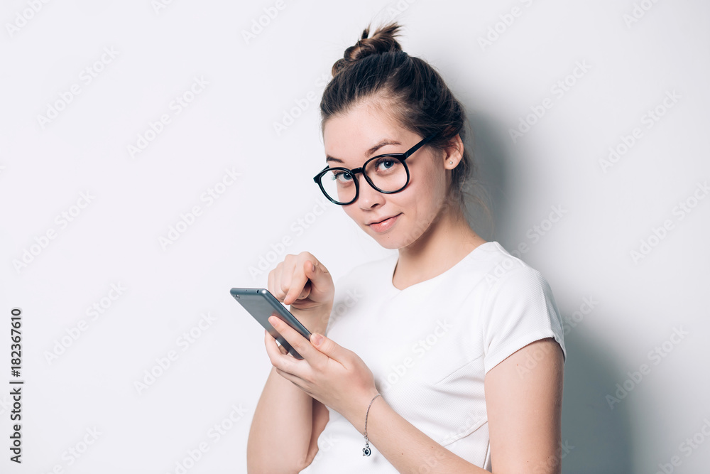 Happy beautiful young woman with long curly hair holding blank screen mobile phone and pointing finger over white background Happy beautiful young woman with long curly hair holding blank screen mobile phone and pointing finger over white background