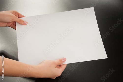 
Female hands with paper on a black background. Studio