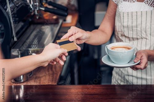 customer pay coffee drink with credit card to barista Close up hand paid for to go coffee cup at counter bar in cafe Food and drink business billing payment.
