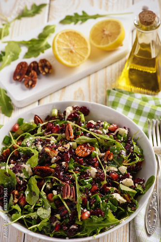 Salad with wild rice, arugula, pomegranate, pecan nuts, cranberries and feta cheese.