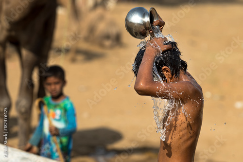 Bath in the desert.A child taking bath in watering trough or puddle in the desert, India. Water concept