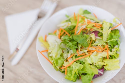 Salad and fresh vegetables on wooden table background