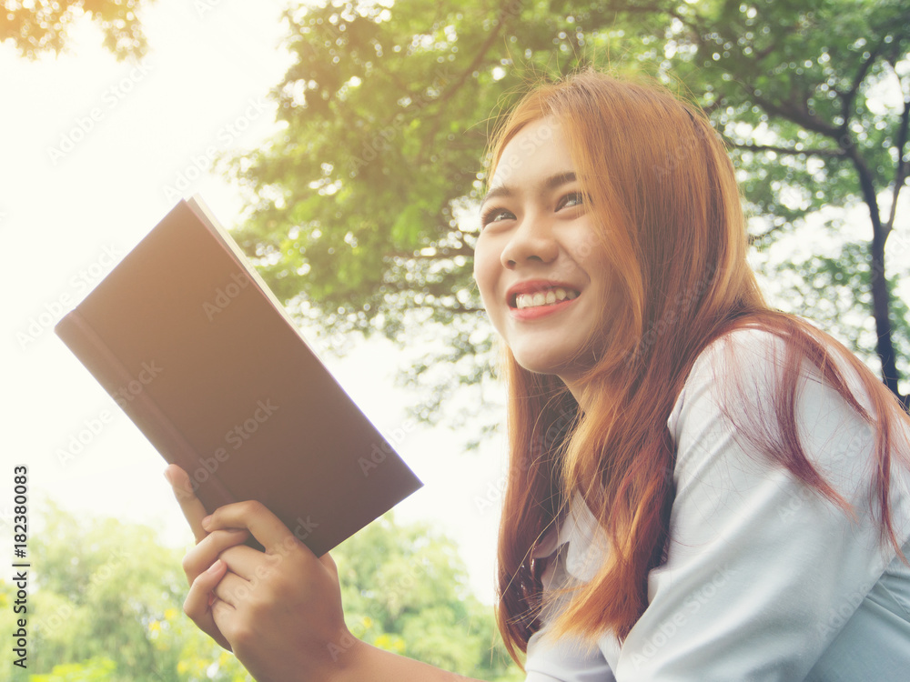 Young woman sitting reading book at the park. Young woman sitting reading book at the park.