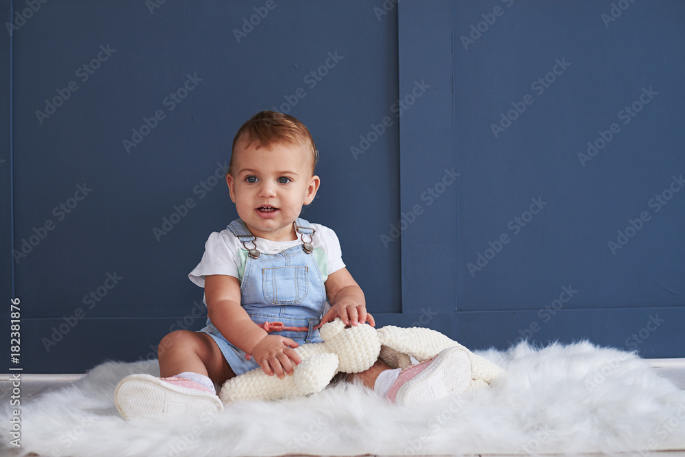Cute blue-eyed baby girl with toy sitting on the floor Cute blue-eyed baby girl with toy sitting on the floor