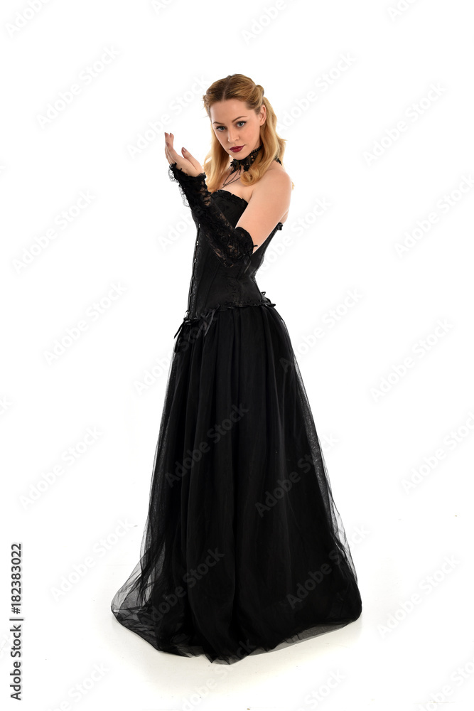 full length portrait of a blonde girl wearing black gothic gown. standing pose, isolated on white background. full length portrait of a blonde girl wearing black gothic gown. standing pose, isolated on white background.