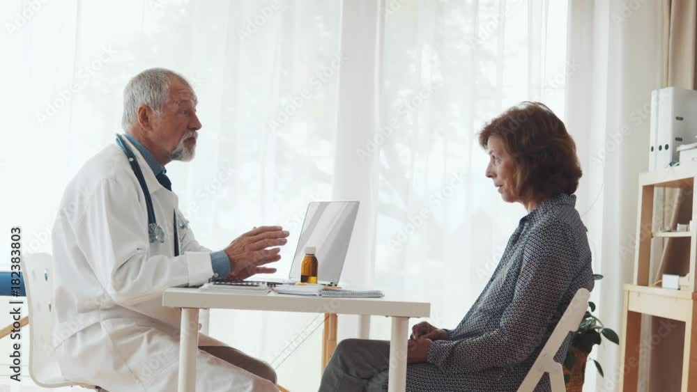 Doctor with laptop talking to a senior woman in office. Doctor with laptop talking to a senior woman in office.