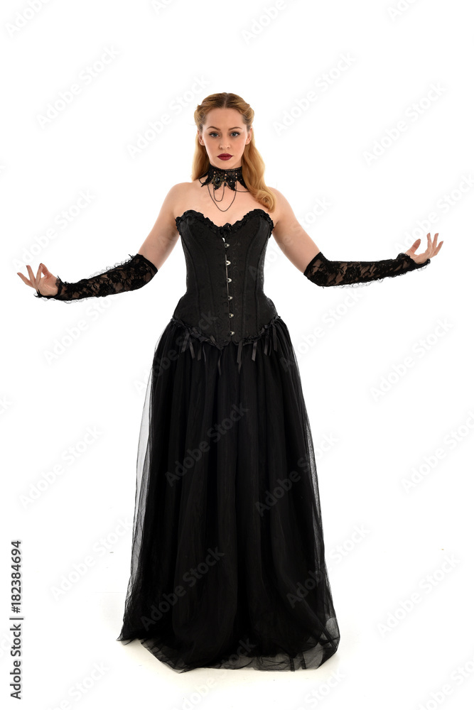 full length portrait of a blonde girl wearing black gothic gown. standing pose, isolated on white background. full length portrait of a blonde girl wearing black gothic gown. standing pose, isolated on white background.
