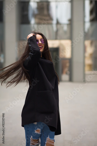 Happy brunette woman with hair blowing in the wind walking at the city mall