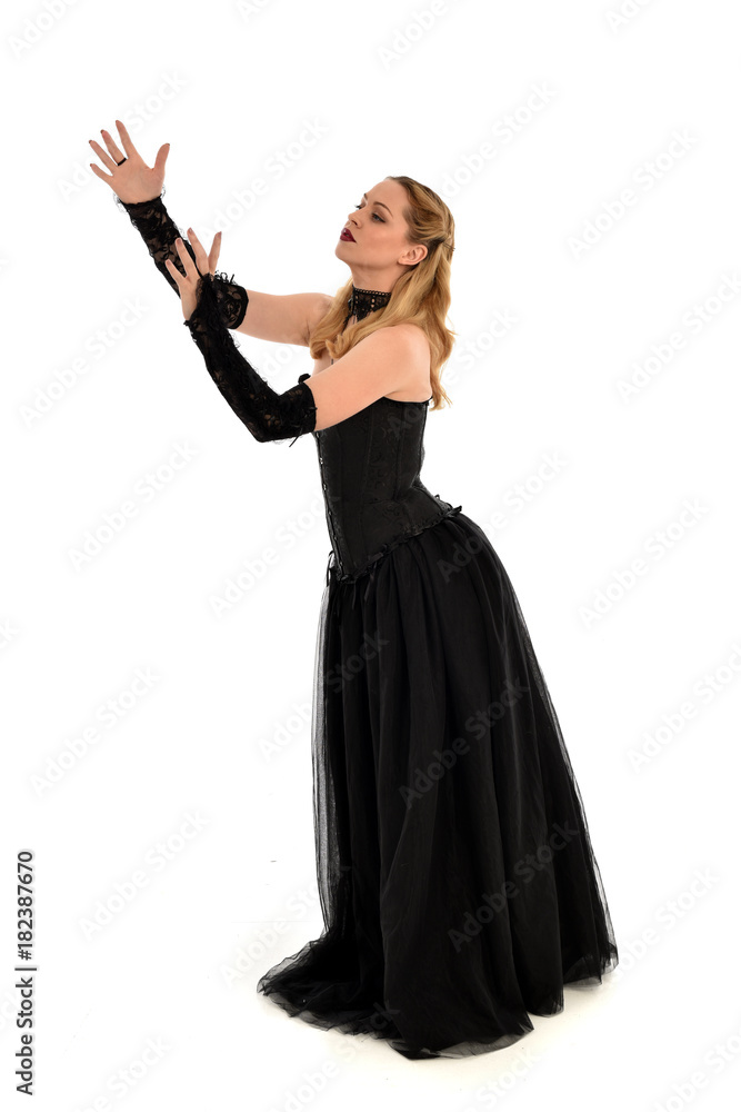 full length portrait of a blonde girl wearing black gothic gown. standing pose, isolated on white background. full length portrait of a blonde girl wearing black gothic gown. standing pose, isolated on white background.