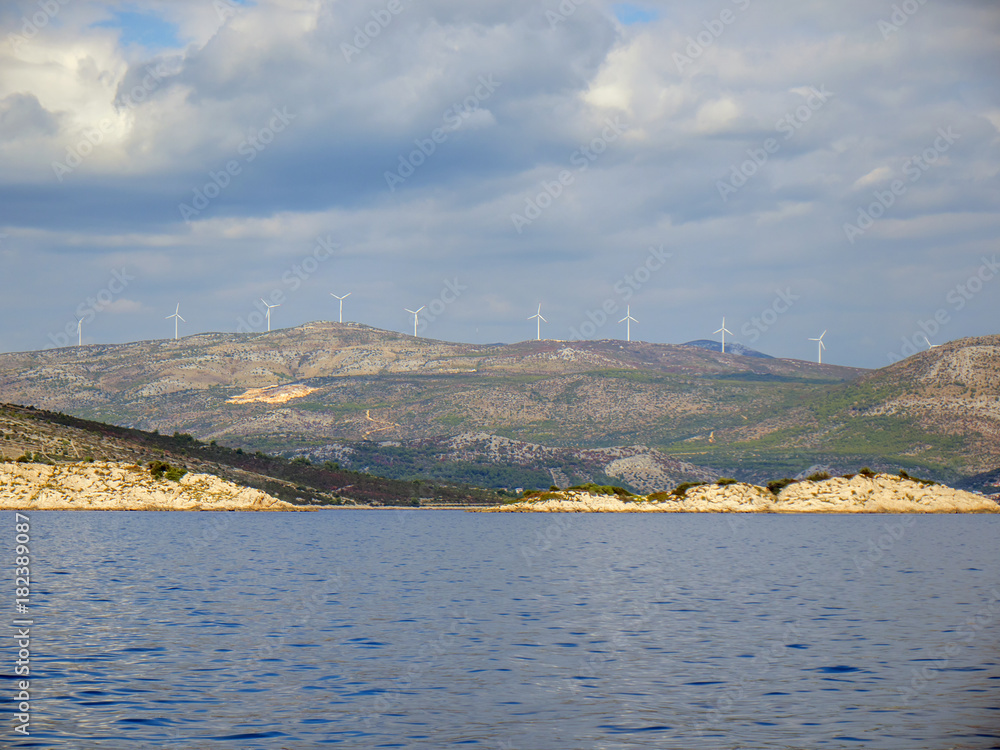 Croatian coastline with wind power generators on hills.