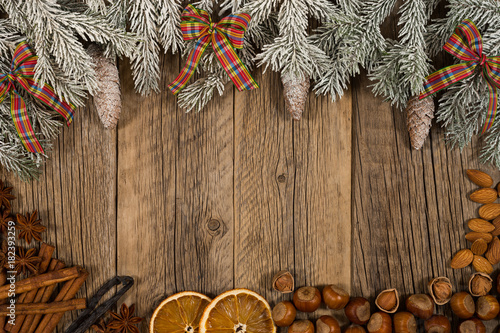 Christmas composition.The branch of spruce with a gift, hazelnuts, oranges on an old wooden table.