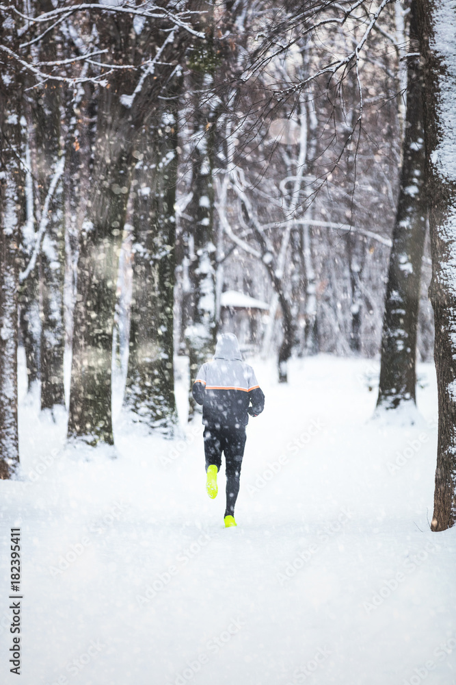 Man exercising / jumping and running in the park filled with snow.