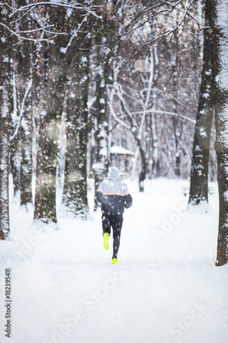 Man exercising / jumping and running in the park filled with snow. © astrosystem